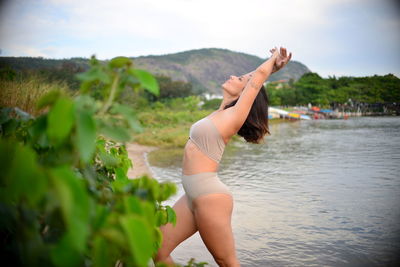 Side view of woman in lingerie exercising by lake