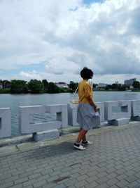 Rear view of boy standing against sky