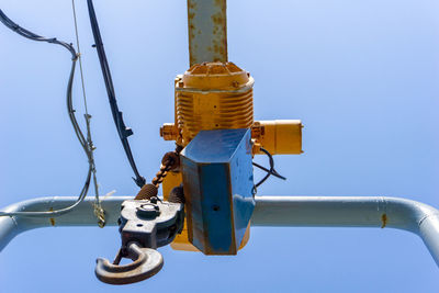 Low angle view of machine part against clear blue sky