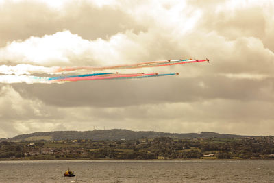 Airplane flying over river against sky