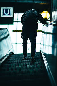 Rear view of man standing on escalator