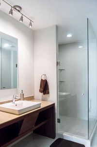 Bathroom with luxury finishes, main mirror with led light from behind, white ceramic washbasin