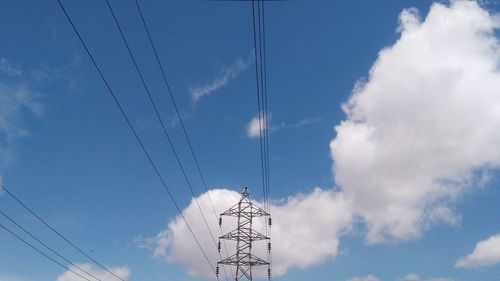 Low angle view of electricity pylon against blue sky