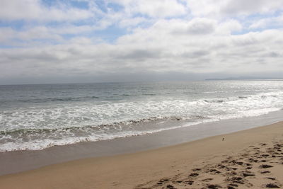 Scenic view of beach against cloudy sky