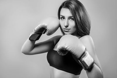 Portrait of young woman in fighting stance over gray background