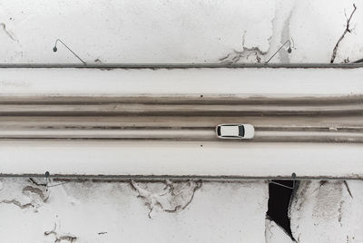 A car travels on a bridge crossing an icy river. there are interesting shapes in the river ice.