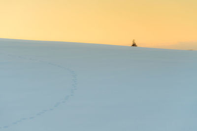 Scenic view of snow covered land against clear sky during sunset