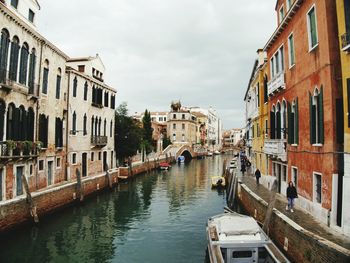 Canal amidst buildings in city against sky