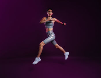 Full length of woman jumping against black background