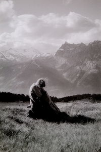 Man sitting on field against sky