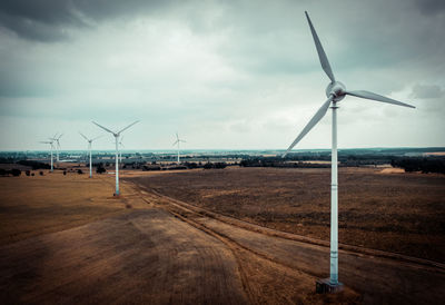 Windmills on field against sky