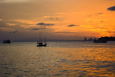 Silhouette boat sailing on sea against sky during sunset