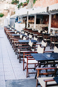 Empty chairs and tables at sidewalk cafe against buildings