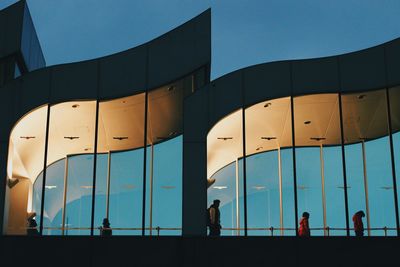 Silhouette people walking on modern building against clear blue sky