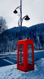 Classic red british telephone box on the snowy street in sinaia, carpathian mountains, romania