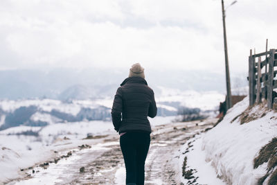 Rear view of woman standing on snow covered mountain