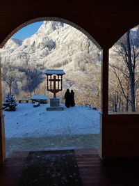 Built structure by trees against sky seen through window