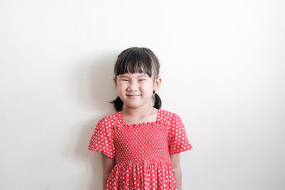 Portrait of a smiling girl standing against white background