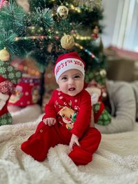 Portrait of cute baby girl sitting on bed at home