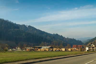 Houses on field by mountain against sky