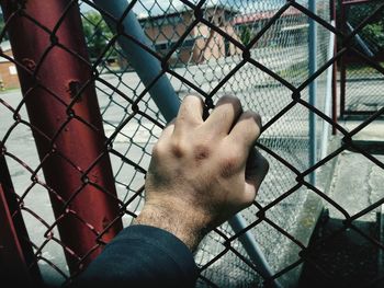 Close-up of hand on chainlink fence