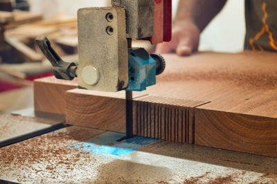 A man cuts wood on a circular saw in a joinery, band saw, holding a plank