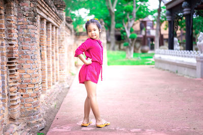 Portrait of a smiling girl standing against pink wall
