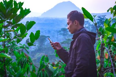 Side view of young man looking at camera