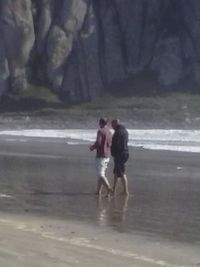 Rear view of couple walking on beach