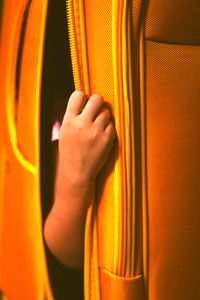 Close-up of hand in orange luggage