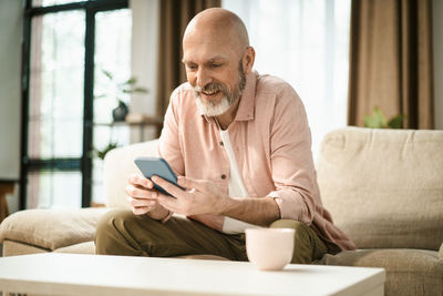 Young man using mobile phone while sitting on sofa at home
