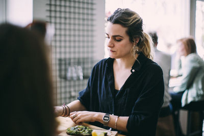 Young woman having food on table at restaurant