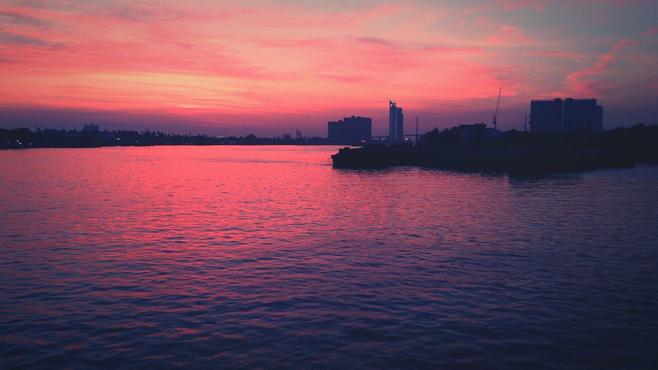 sunset, water, sky, waterfront, building exterior, architecture, built structure, orange color, sea, scenics, silhouette, beauty in nature, tranquil scene, tranquility, rippled, cloud - sky, dusk, river, nature, dramatic sky