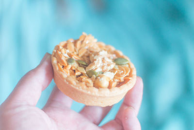 Cropped hand of person holding mini tart outdoors