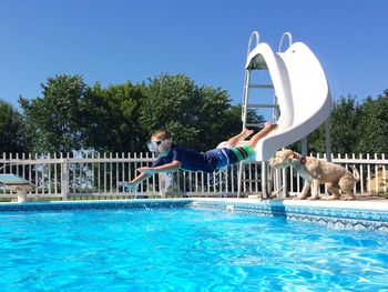 Full length of boy jumping in swimming pool during summer