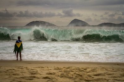 Rear view of man looking at sea against sky