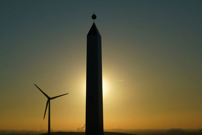 Silhouette of wind turbine against sky during sunset
