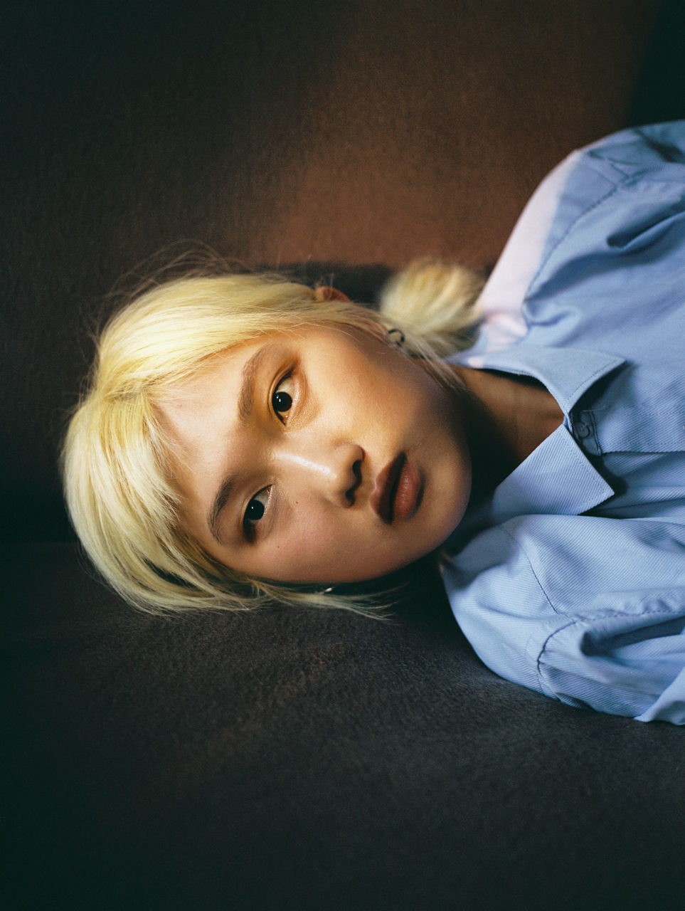 portrait, lying down, one person, blond hair, real people, hair, indoors, looking at camera, relaxation, young adult, headshot, leisure activity, young women, women, lifestyles, adult, close-up, lying on back, hairstyle, beautiful woman, contemplation, innocence