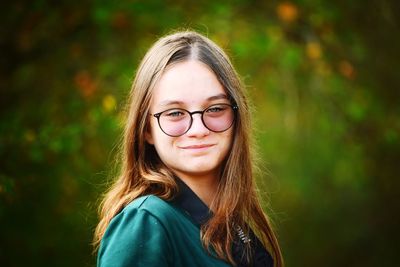 Portrait of young woman standing against plants