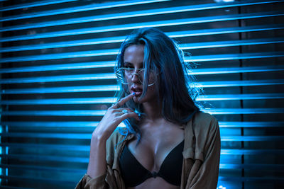 Young woman standing by window at night