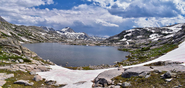 Scenic view of lake by snowcapped mountains against sky