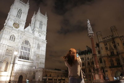 Rear view of woman standing against buildings in city