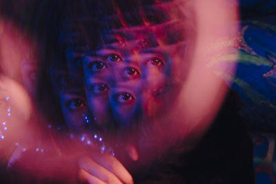 Multiple exposure of woman's eye at illuminated bar