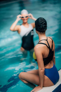 Young women resting, poolside, indoor pool. recreational swimming.