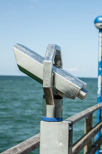 Close-up of metal against sea against clear sky