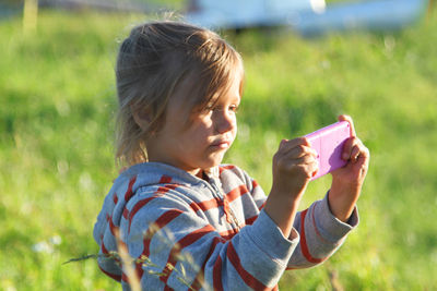 Cute girl playing video game standing outdoors