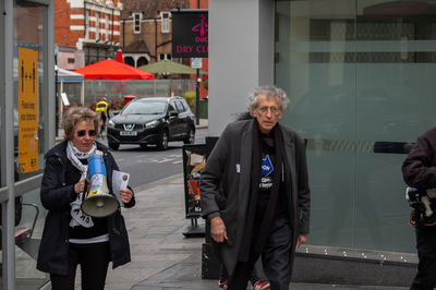 Full length of friends walking on street in city