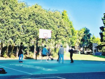 People playing basketball court against blue sky