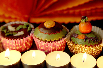 Close-up of halloween cupcakes and lit candles on table