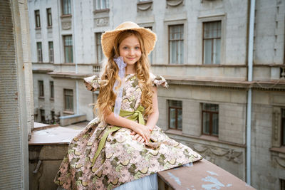 Little girl in dress and hat posing on the balcony